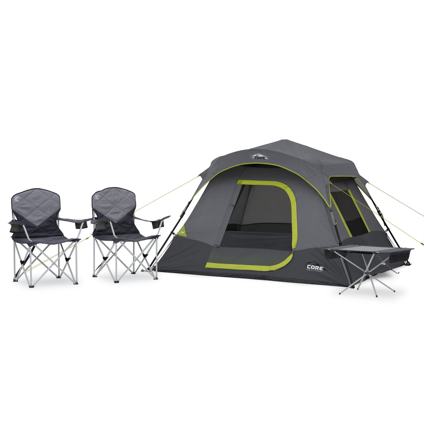 A grey and green CORE 4 person instant cabin tent is set up with its front door closed. To the left of the tent, there are two foldable camping chairs. To the right of the tent is a small, foldable table. The tent, chairs and table are placed on a simple white background.